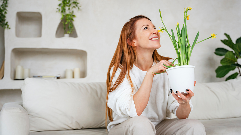a women with happy smile holding a plant, breathing fresh air