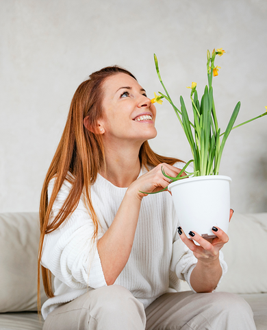 a women with happy smile holding a plant, breathing fresh air