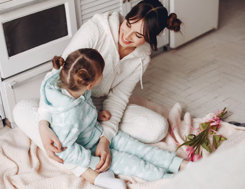 mom and cute girl smiling at each other, hugging each other