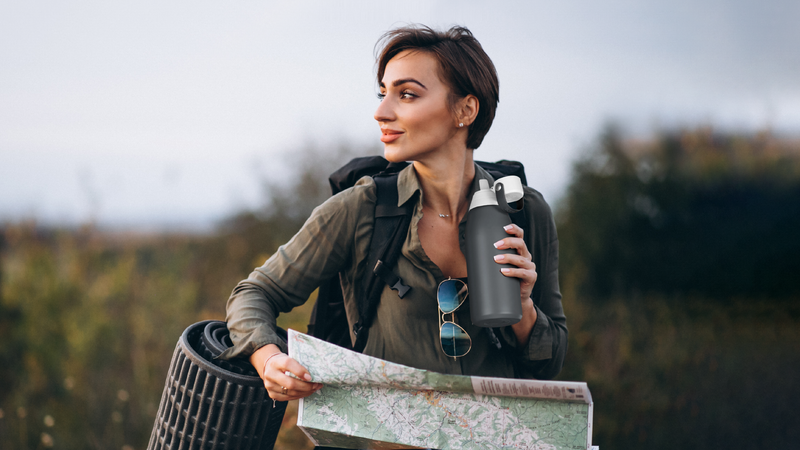 Hiker with camping gear and a map, drinking from a water bottle using Fil-Fresh replacement filter