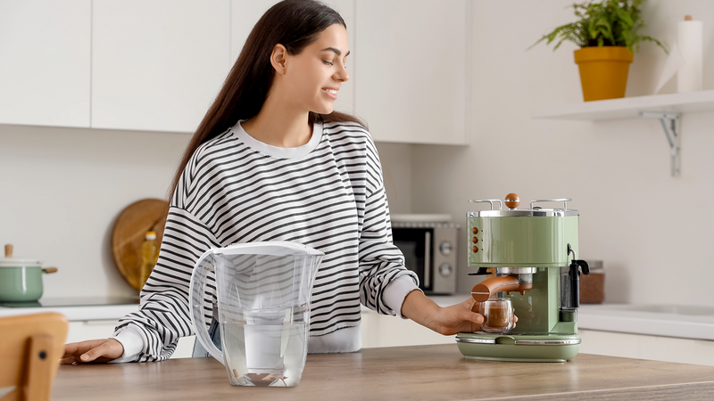 Young woman making coffee with an espresso machine using filtered water to help reduce limescale