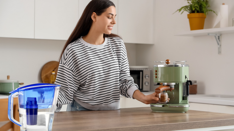 Young woman making coffee with an espresso machine using filtered water to help reduce limescale