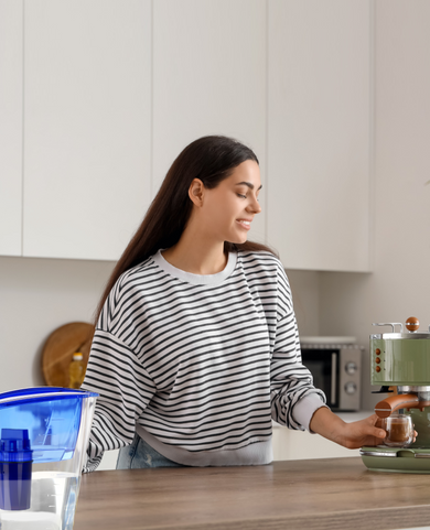 Young woman making coffee with an espresso machine using filtered water to help reduce limescale