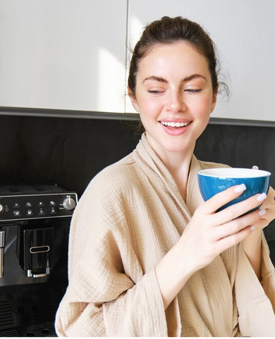 Woman relaxing with a fresh cup of coffee made using filtered water by the kitchen coffee machine