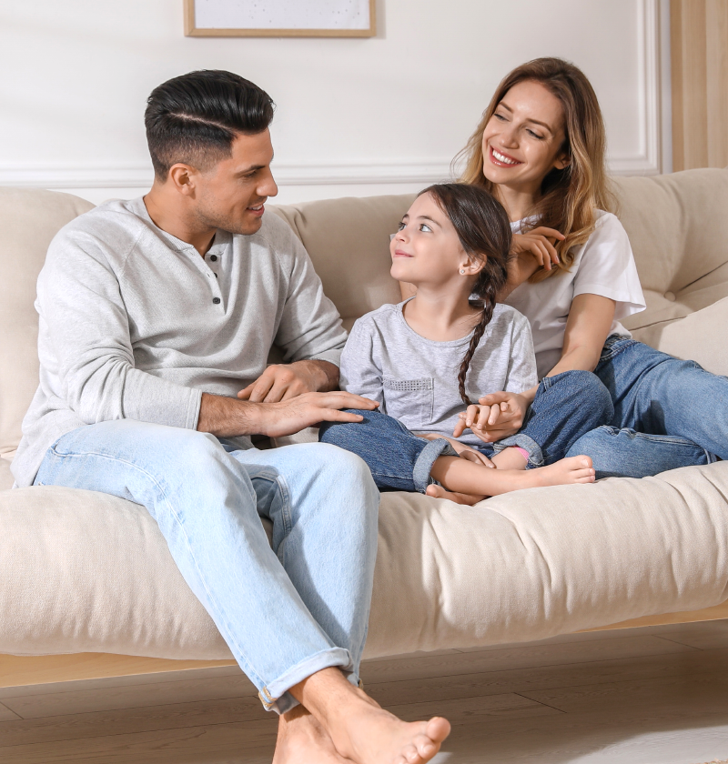 Happy family laughing and chatting together on the couch, enjoying a cozy home environment with Fil-Fresh filtration