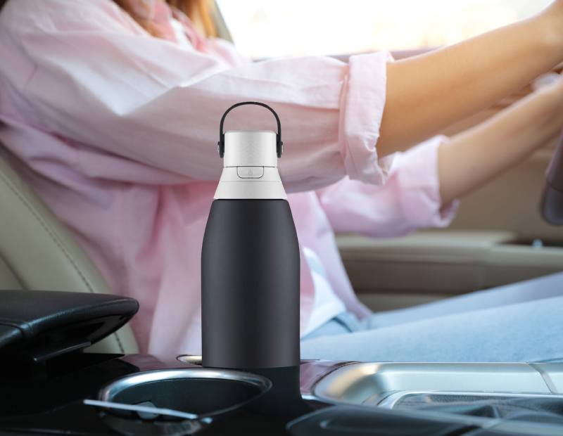 Woman driving with a Brita water bottle in center armrest box, using Fil-Fresh water bottle filter for fresh hydration on the go