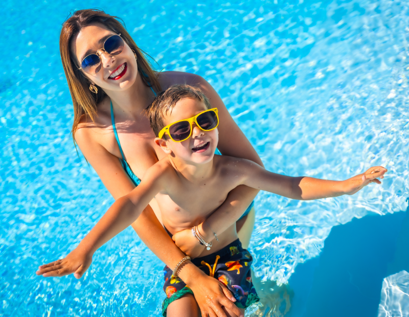 Mother and child hug in a crystal-clear pool, enjoying carefree moments made for summer