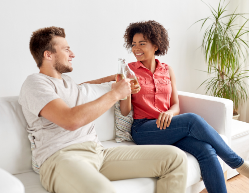 Smiling couple toasting with glasses of water on the couch