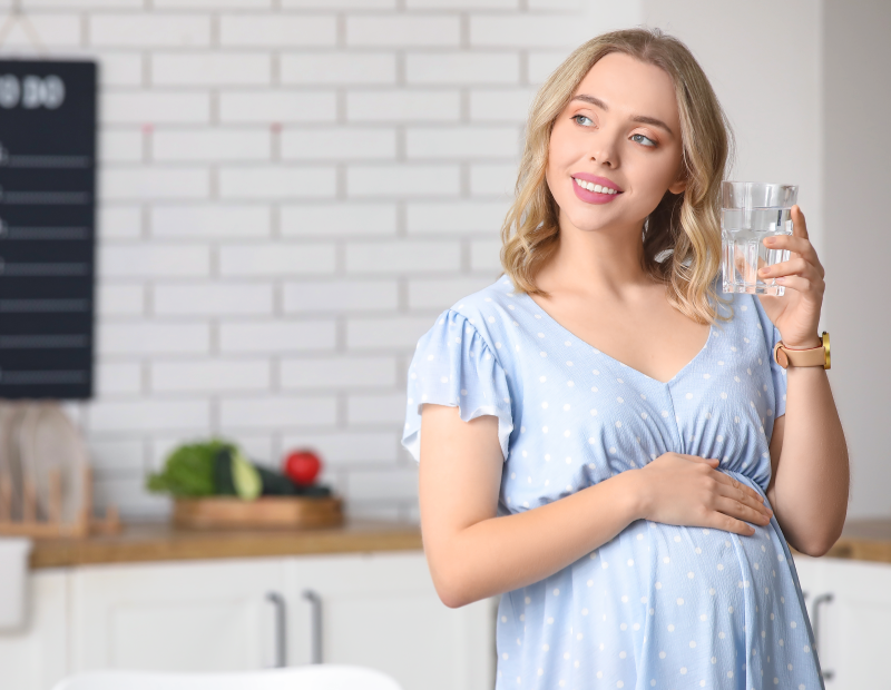 Smiling pregnant woman holding a glass of water filtered by Fil-Fresh pitcher water filter