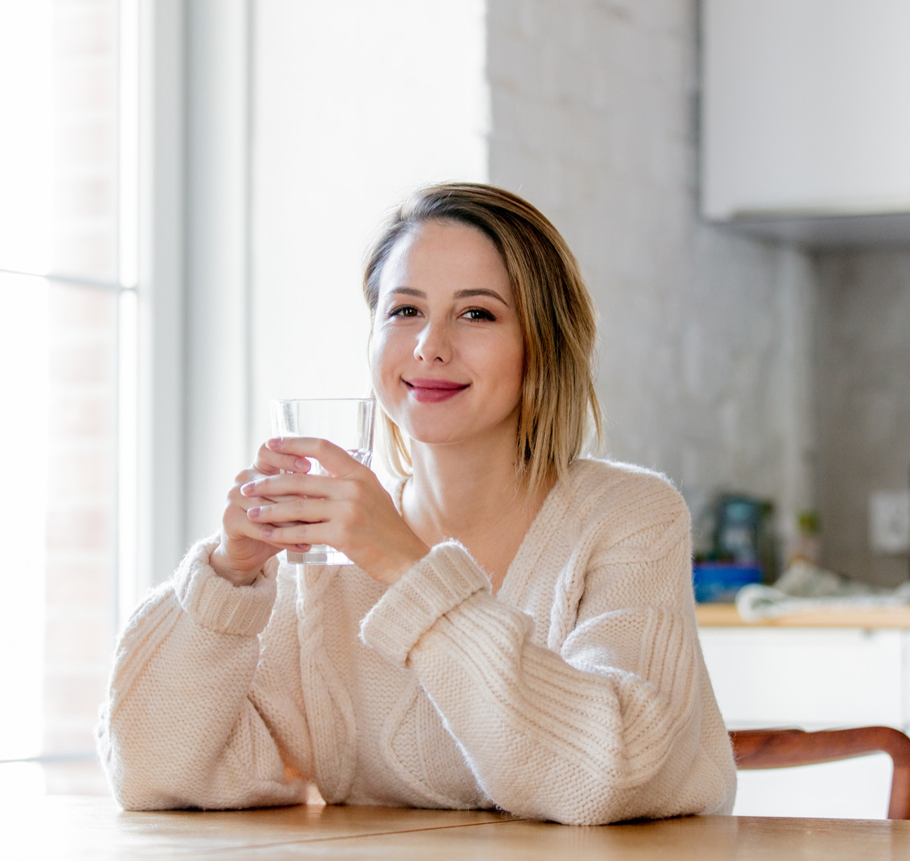 A smiling graceful woman holding a glass of water, reflecting the joy of fresh, healthy living with Fil-Fresh water filters